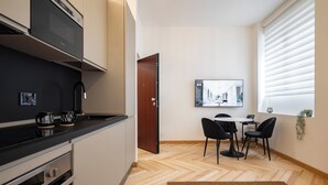 A modern kitchen with a black countertop, stainless steel appliances, and a dining area with a table and chairs.