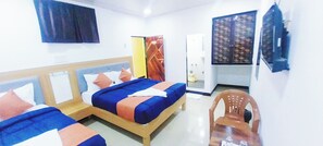A hotel room with two beds, a wooden headboard, a mirror, a chair, and a wall-mounted TV. - Hotel jazz (Mumbai)