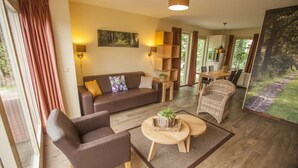 Een moderne woonkamer met een bank, fauteuils, een salontafel en een eethoek met een tafel en stoelen.