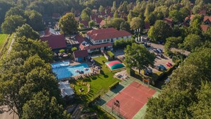 Luchtbeeld van een woonwijk met huizen, een zwembad en een tennisbaan.