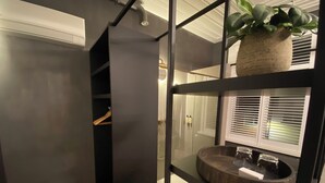 Un baño moderno con separador de vidrio, tocador de madera y una planta en maceta.