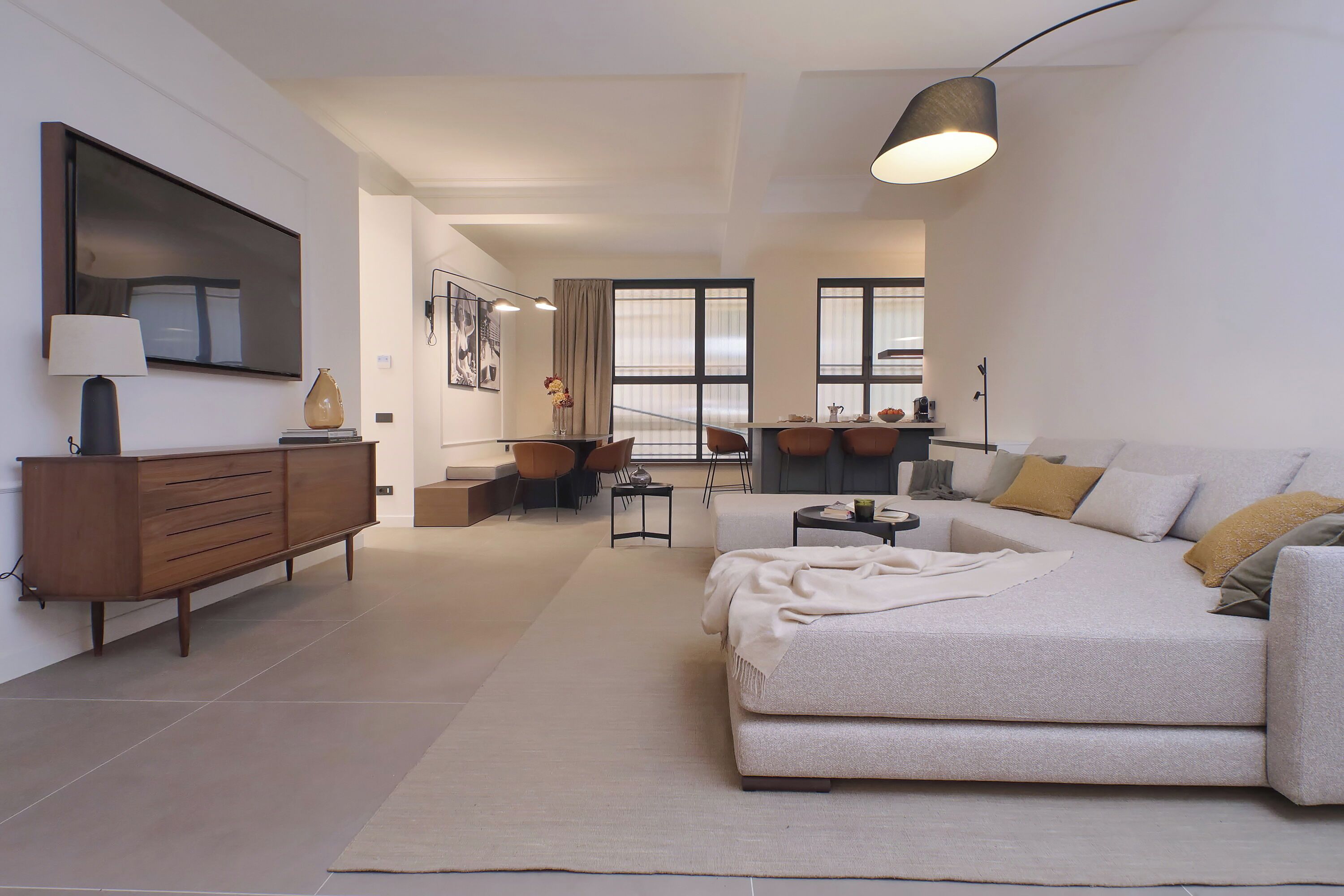 A modern living room with a sofa, a coffee table, and a dining area with chairs and a table.