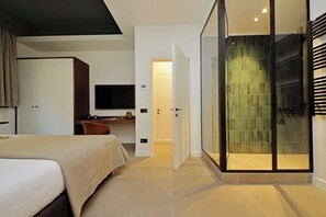 A modern hotel room with a bed, a desk, a television, and a sliding glass door leading to a shower area. - Crispi Loft (Rome)