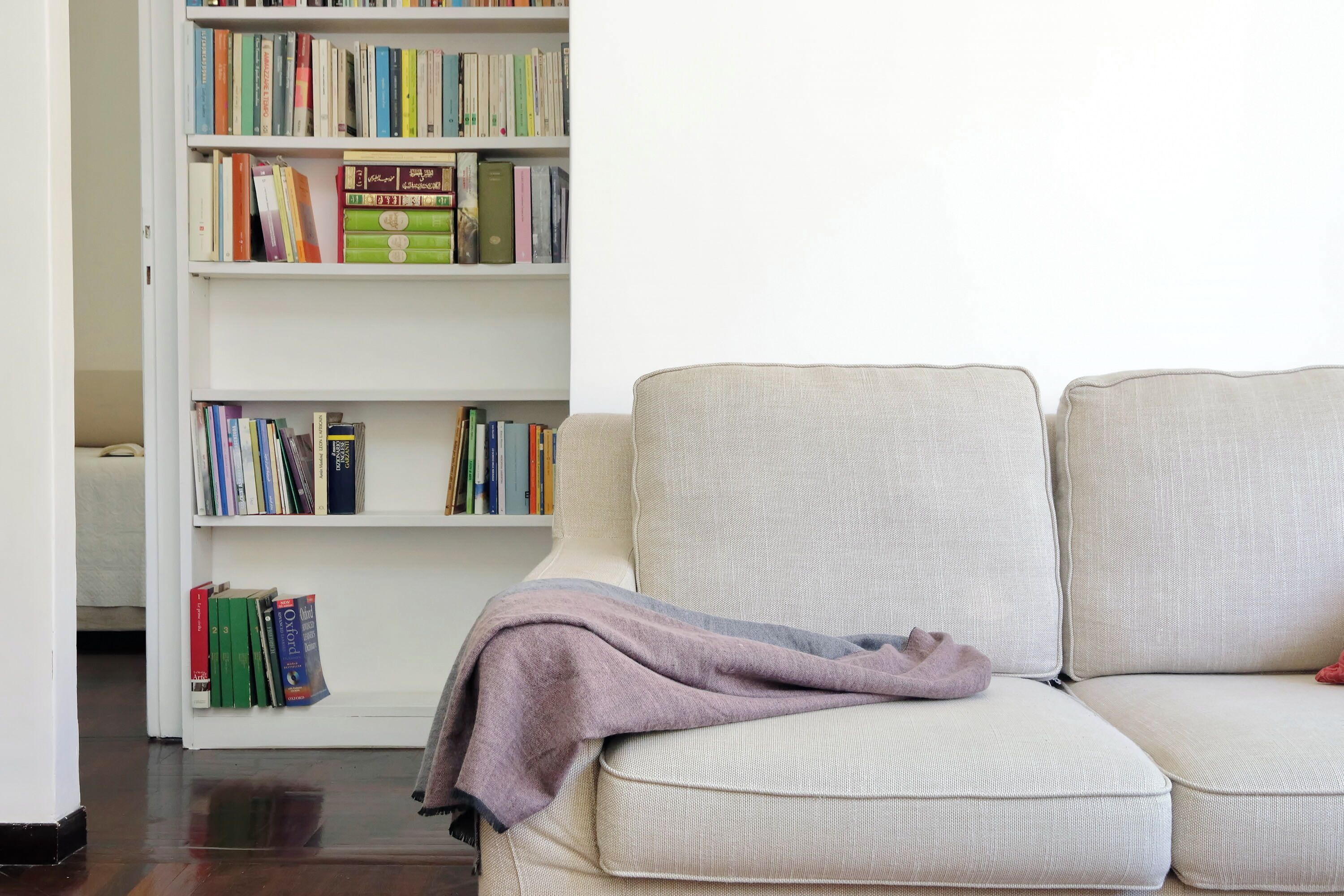 Ein Zimmer mit einem beigen Sofa und einem Bücherregal voller Bücher.
