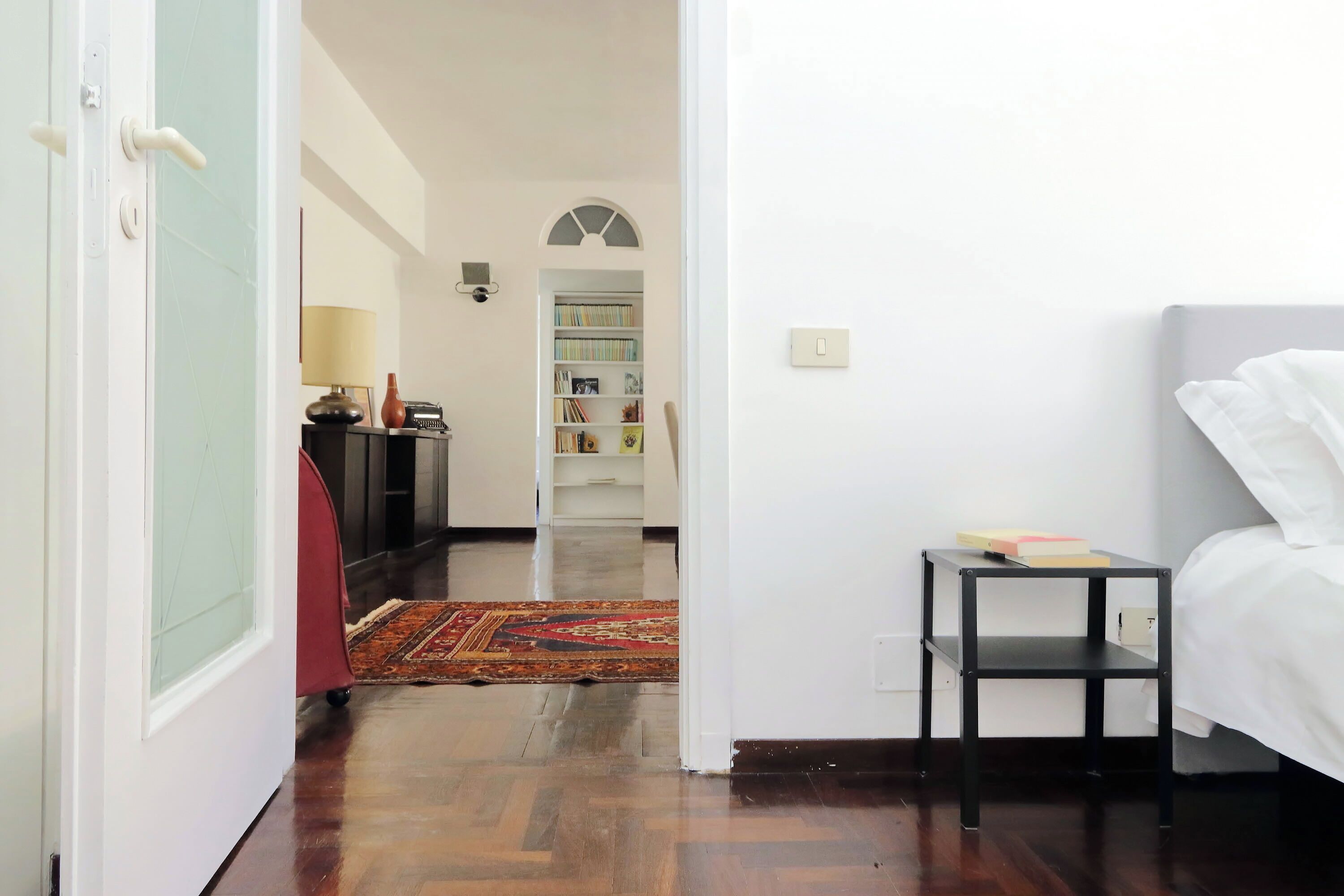 Une chambre à coucher avec un lit, une petite table et une bibliothèque en arrière-plan.