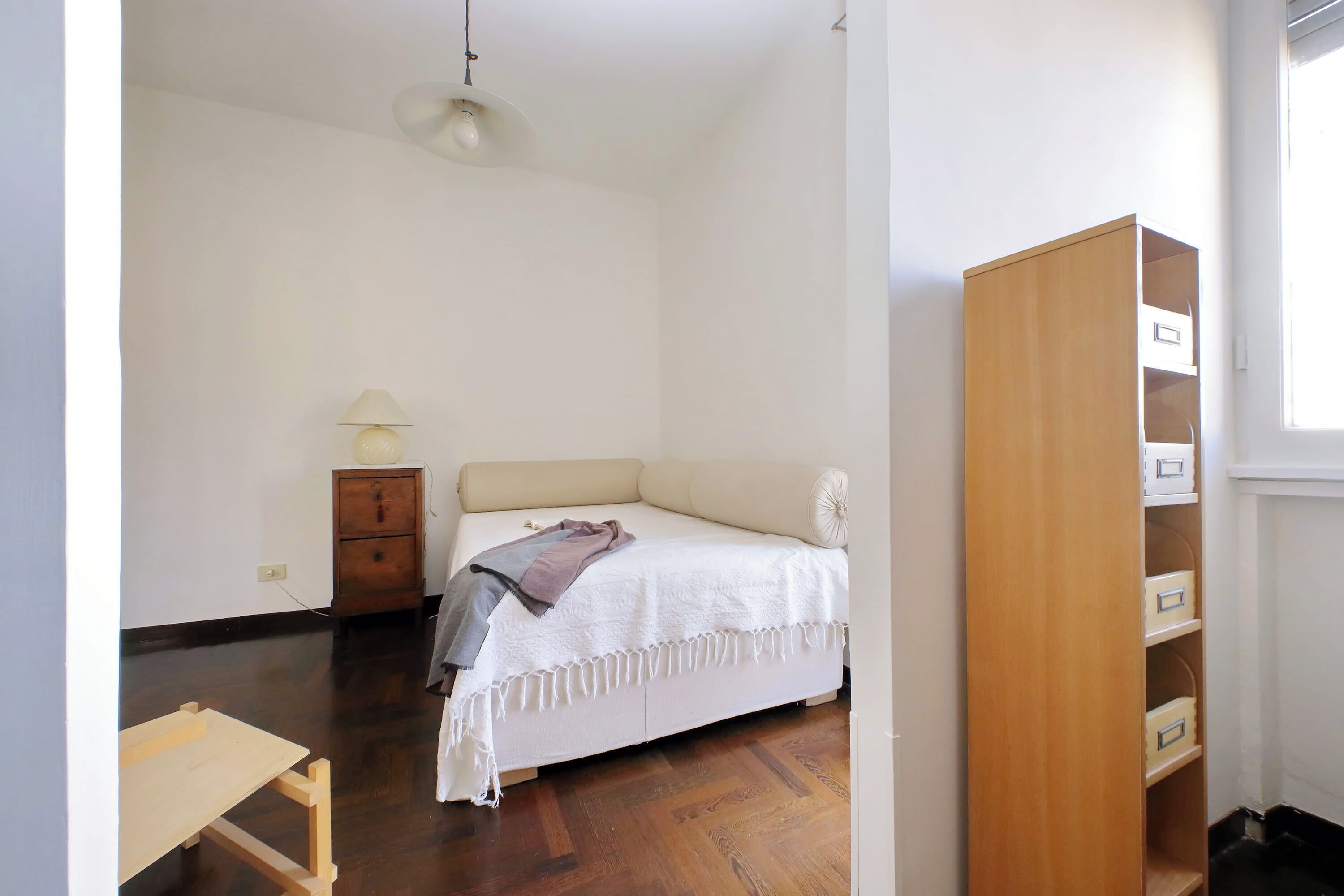 A bedroom with a bed, wooden dresser, and a small table.