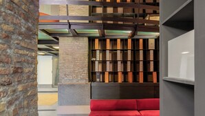 A library with bookshelves, a red cushioned bench, and a brick wall. - Santa Cecilia Loft (Rome)