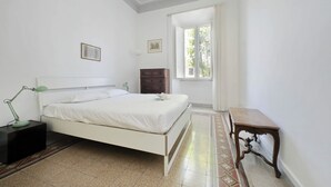 A bedroom with a bed, a nightstand, a desk, and a window. - Cozy Merulana (Rome)