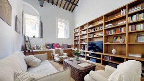 A cozy living room with a sofa, armchairs, a coffee table, and a bookshelf filled with books. - Ottavia Terrace (Rome)