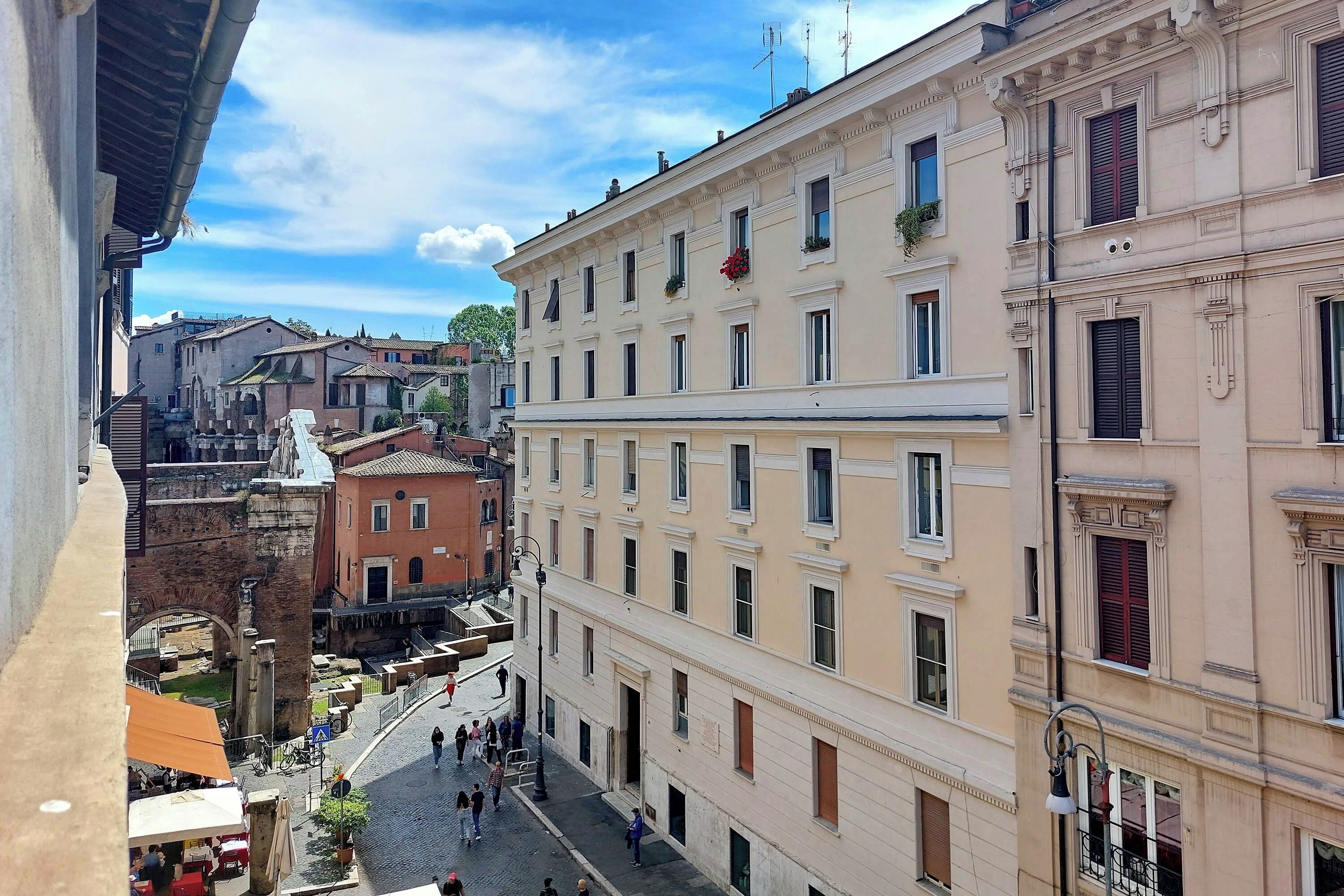 Una calle estrecha con edificios históricos, una estatua y un camino adoquinado.