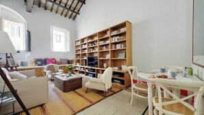A spacious living room with a large bookshelf, a dining table with chairs, and a comfortable seating area. - Ottavia Terrace (Rome)