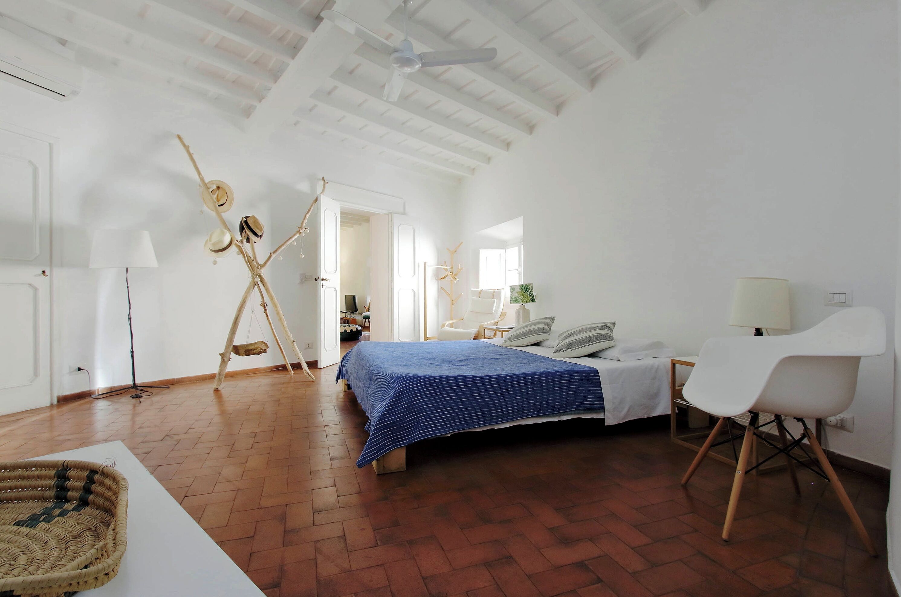 A bedroom with a bed, a chair, a lamp, and a ceiling fan.