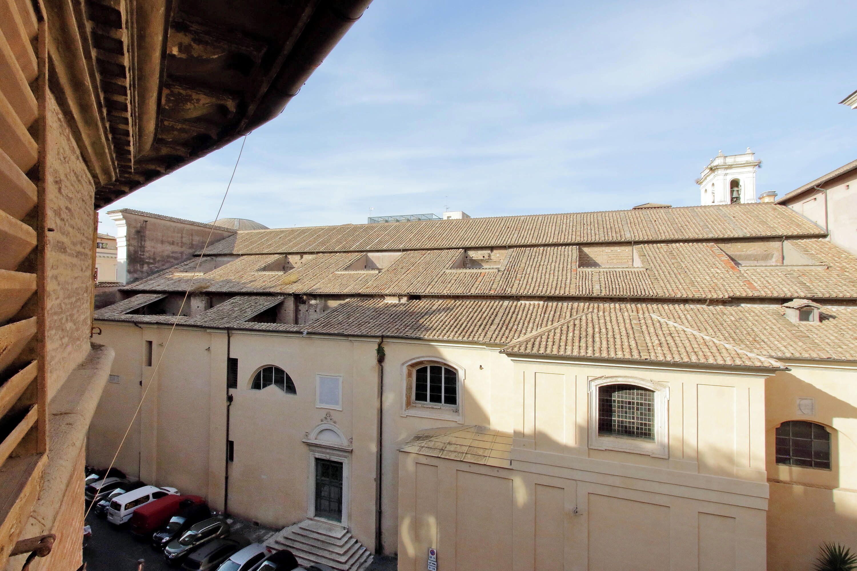 A narrow street with buildings featuring tiled roofs and arched windows.