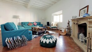 A spacious living room with a high ceiling, a fireplace, a sofa set, a coffee table, and a magazine rack. - Charming Minerva (Rome)