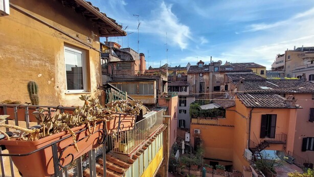 A residential building with a balcony, potted plants, and a clear view of the surrounding neighborhood. - Charming Minerva (Rome)