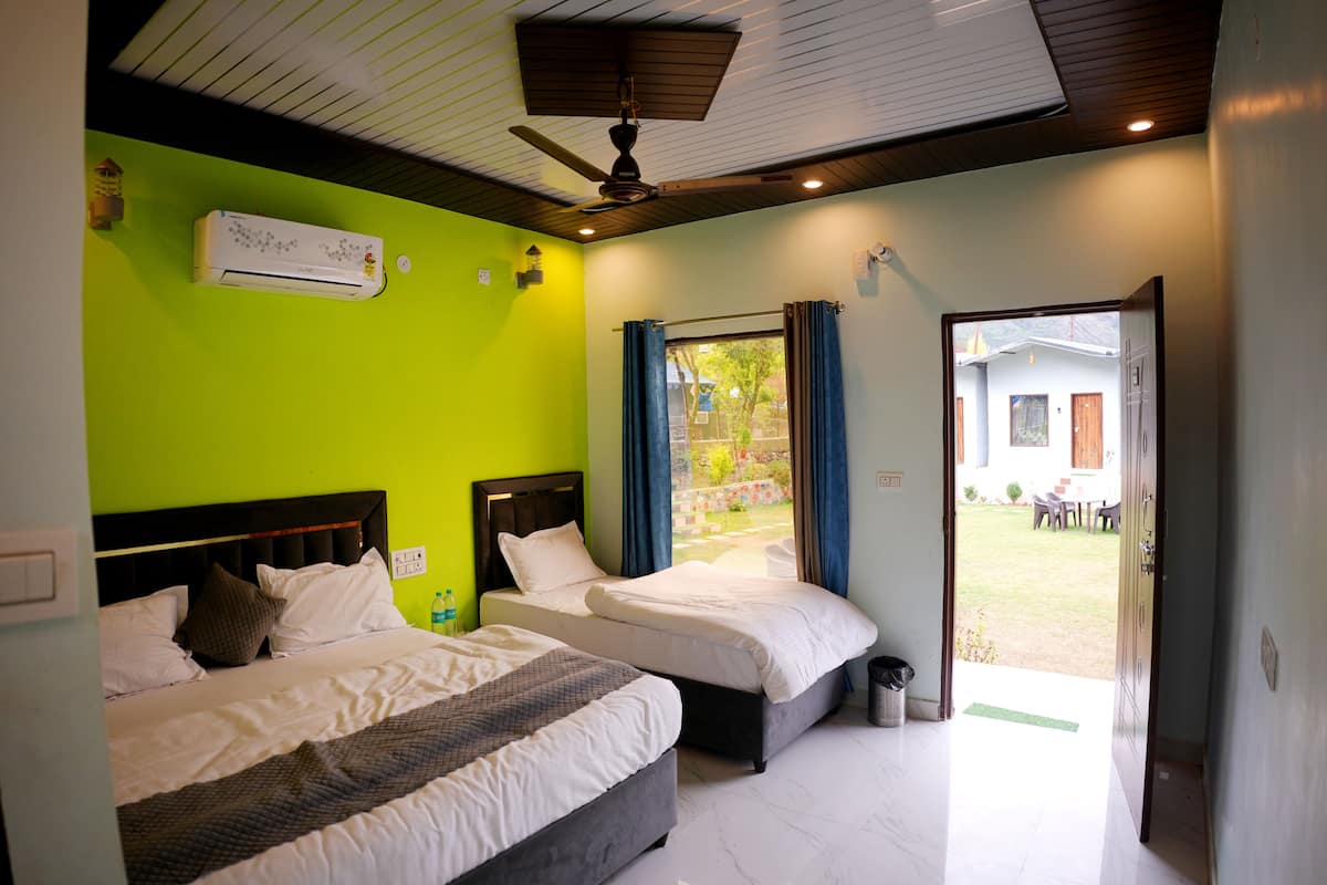 A hotel room with two beds, a ceiling fan, an air conditioning unit, and a view of the outside.