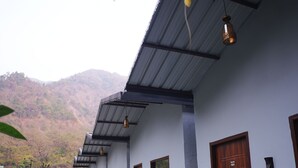 A building with a long corridor, multiple doors, and a garden area with a pathway.