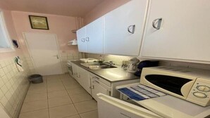 Una cucina compatta con mobili bianchi, un forno a microonde e un frigorifero.