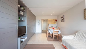 Una sala de estar moderna con un sofá, televisor y comedor con una mesa y sillas.