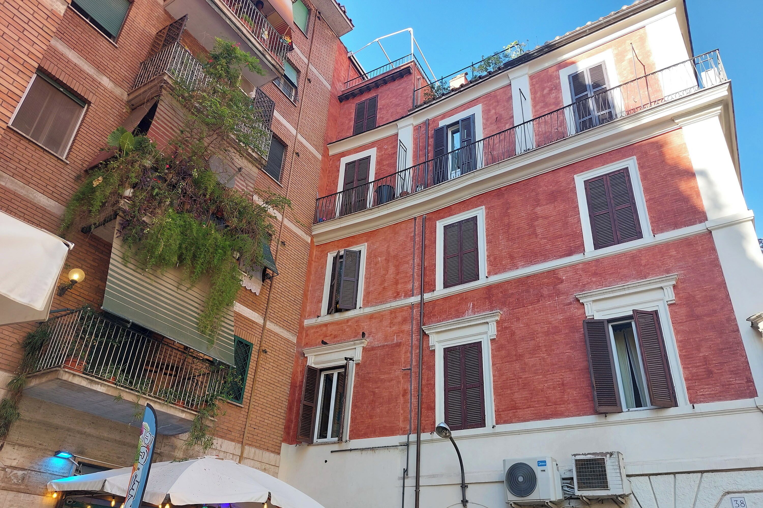 Un edificio de varios pisos con paredes de ladrillo rojo, detalles blancos y múltiples balcones.