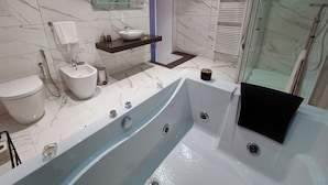 A modern bathroom with a large bathtub, a bidet, a sink, and a glass shower enclosure. - La Residenza del Barone (Camerota)