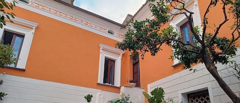 A building with a bright orange facade, white trim, and a set of stone steps leading to a door.