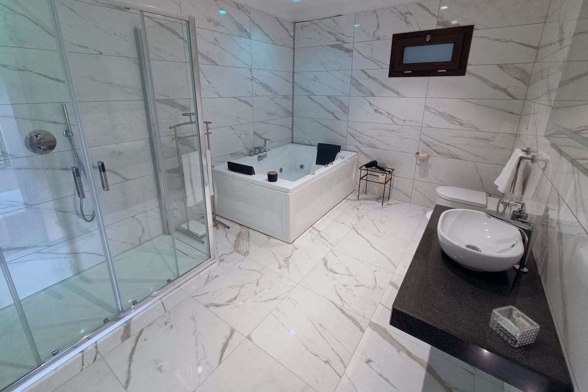 Un baño moderno con ducha envuelta en vidrio, una bañera independiente, un tocador con lavabo y un inodoro.