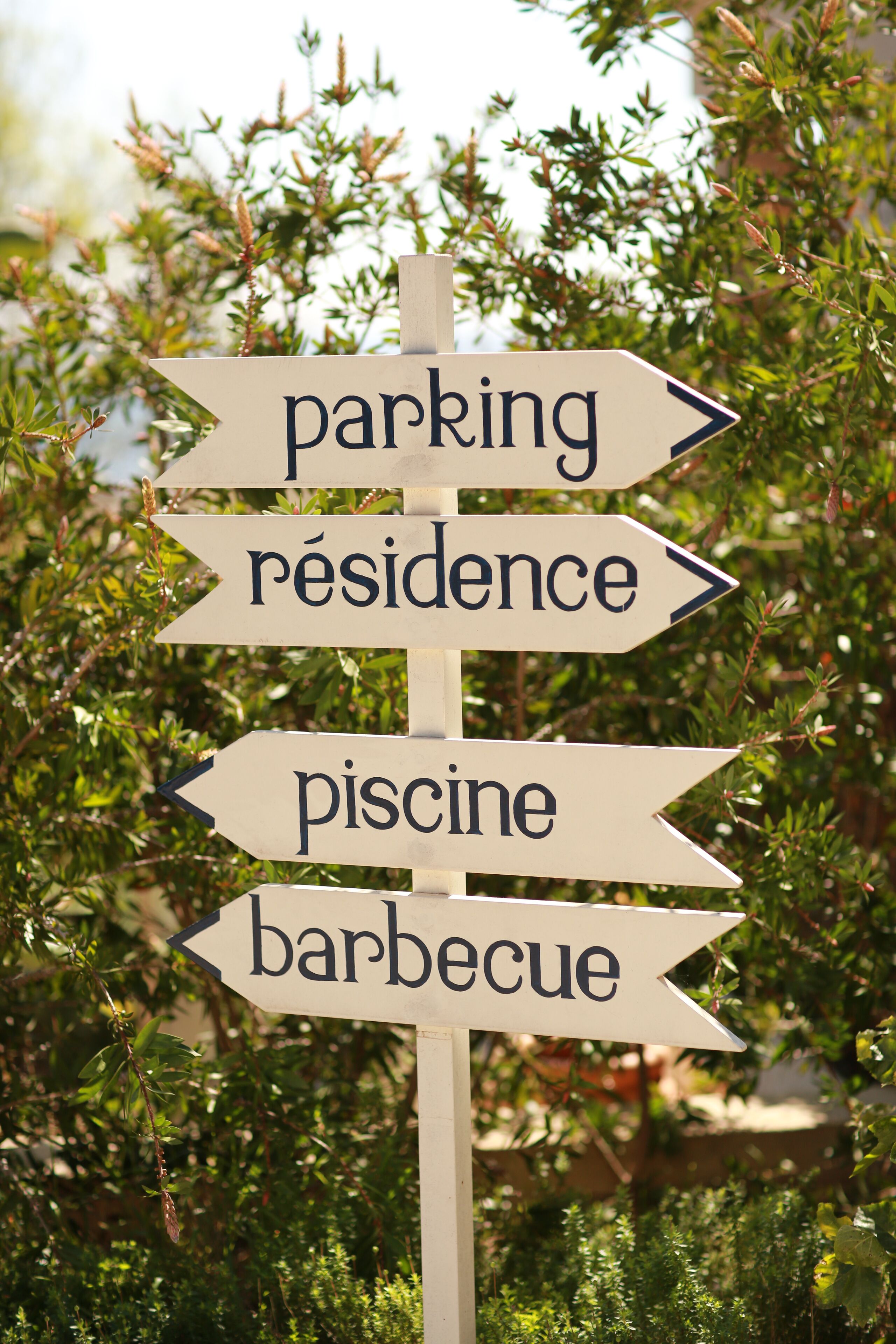 A directional sign with arrows pointing to 'parking,' 'residence,' 'piscine,' and 'barbecue.'