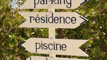 A directional sign with arrows pointing to 'parking,' 'residence,' 'piscine,' and 'barbecue.'