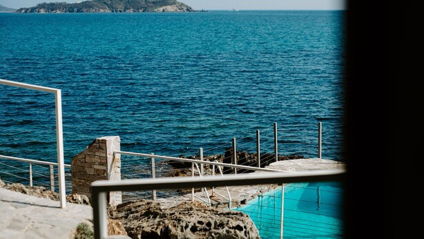 A coastal view with a clear blue sea, a rocky shoreline, and a swimming pool. - La Résidence Le Provençal (Hyères)