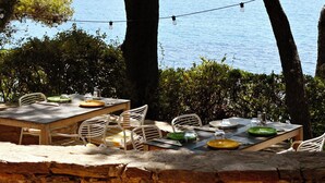 An outdoor dining area with tables and chairs, overlooking a body of water. - La Résidence Le Provençal (Hyères)