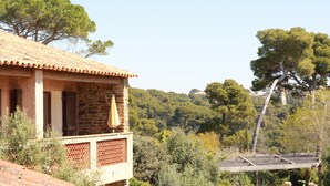 A stone building with a tiled roof, a balcony with a yellow umbrella, and a view of a forested hill. - La Résidence Le Provençal (Hyères)