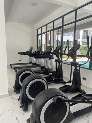 Un gimnasio con cintas de correr, elípticas y máquinas de pesas.
