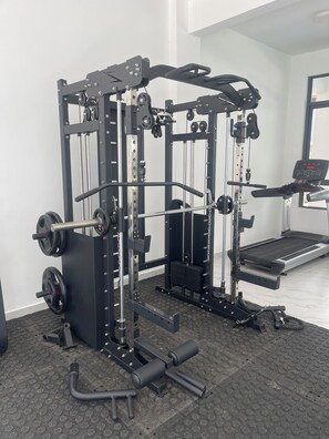 A gym with a weight bench, squat rack, and treadmill.