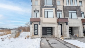 Un immeuble résidentiel à plusieurs étages, doté d’une façade en briques, d’appartements numérotés et d’une entrée de garage.