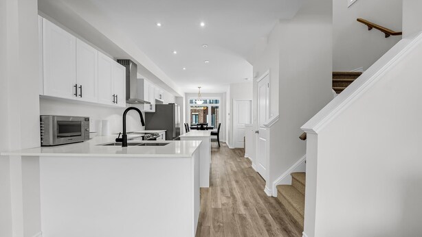 Une cuisine moderne avec des meubles blancs, un îlot central et un plancher en bois.