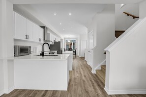 Una cocina moderna con armarios blancos, una isla central y suelo de madera.