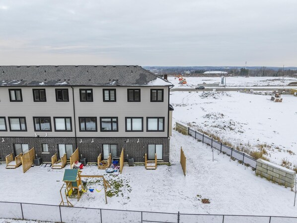 Un edificio de varios pisos con techo plano, sección inferior de ladrillo y suelo cubierto de nieve.