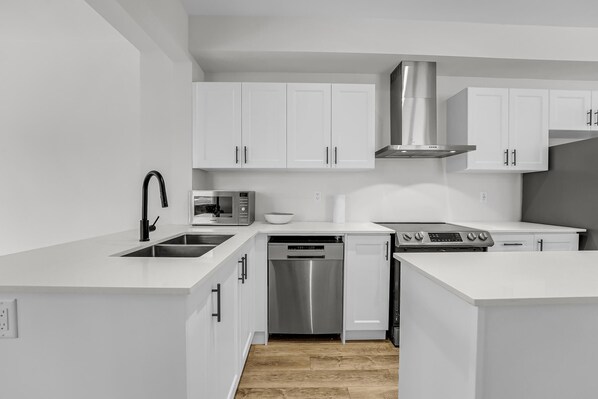 Una cocina moderna con armarios blancos, electrodomésticos de acero inoxidable y lavavajillas.