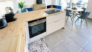 A modern kitchen with a wooden countertop, built-in oven, and a dining area with a round table and chairs. - 3 bedroom townhouse with garden, terrace and private parking (Reims)