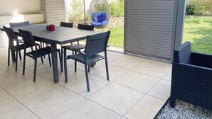 An outdoor patio with a table and chairs, a hanging chair, and a view of a garden. - 3 bedroom townhouse with garden, terrace and private parking (Reims)