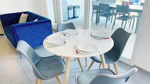 A dining area with a round table set for four, surrounded by four grey chairs with wooden legs. - 3 bedroom townhouse with garden, terrace and private parking (Reims)