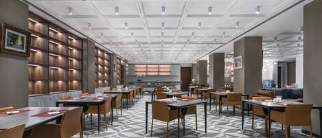 A modern restaurant with a geometric patterned floor, multiple tables and chairs, and a ceiling with recessed lighting.