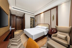 Ein Hotelzimmer mit einem großen Bett, einem Flachbildfernseher, einer Couch und einem Schreibtisch.