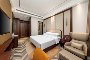 A hotel room with a large bed, a flat-screen TV, a sofa, and a desk.