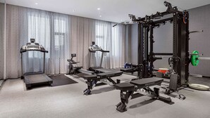 A modern hotel gym with treadmills, weight machines, and a squat rack.