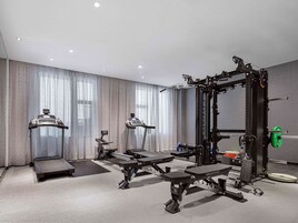 A modern hotel gym with treadmills, weight machines, and a squat rack.