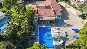 Une grande maison avec une piscine, un court de tennis et un jardin.