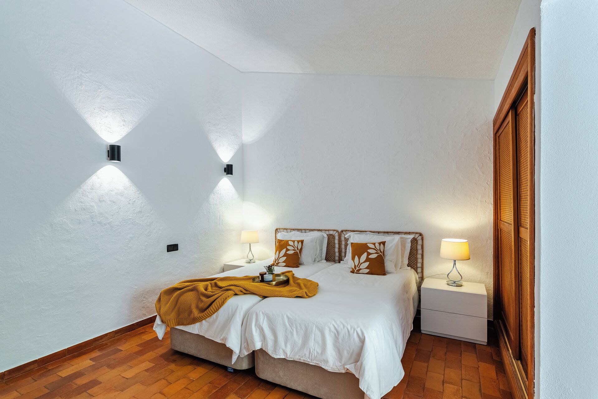 Une chambre à coucher avec un lit, des tables de chevet, des lampes et une armoire en bois.