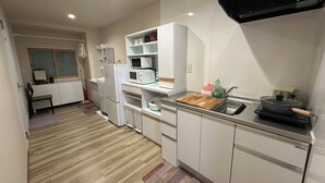 A compact kitchen with white cabinets, a microwave, a refrigerator, and a wooden countertop. - KAIYOUTATEISHI (Tokyo)